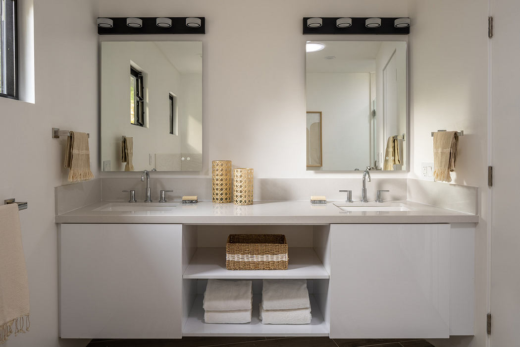 Modern bathroom vanity with twin sinks, mirrors, and neutral decor.