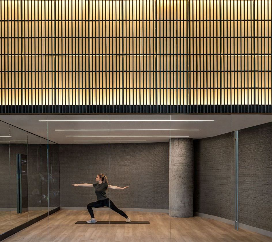 Person practicing yoga in a modern room with sleek wood slats ceiling and glass walls