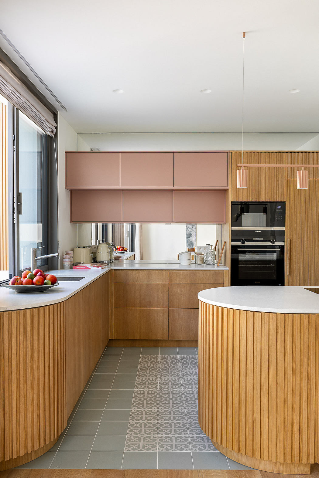 Modern kitchen with curved wooden cabinets and pink upper units.
