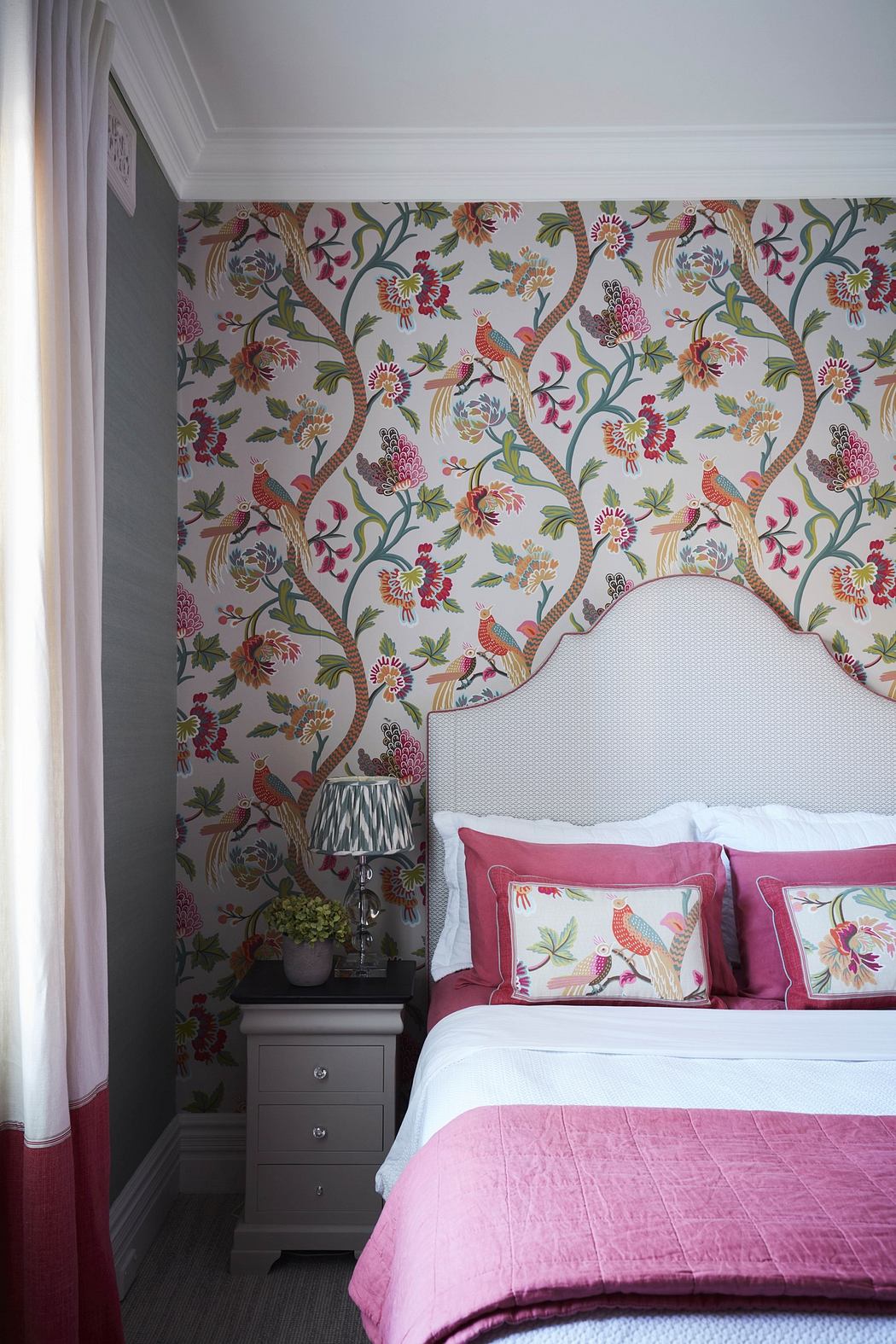 Elegant bedroom with floral wallpaper and pink bedding.