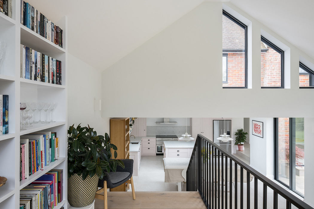 Modern mezzanine interior with kitchen, bookshelf, and staircase.