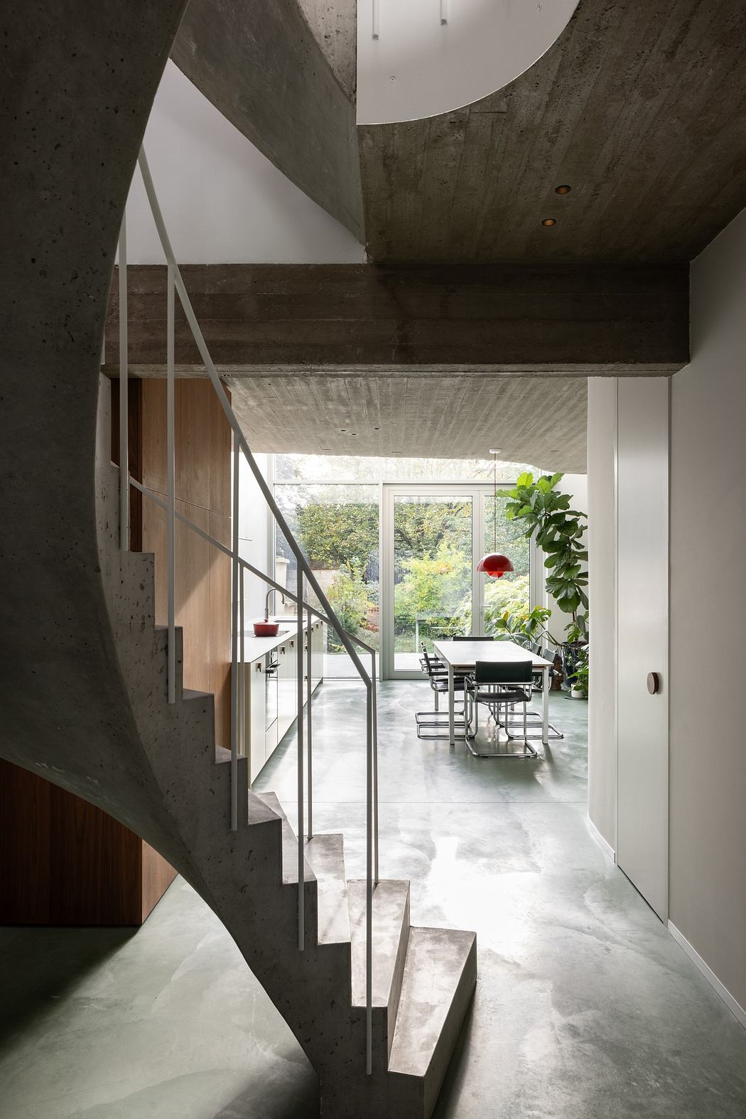 Modern interior with concrete spiral staircase and garden view.