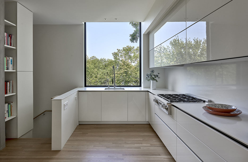 Modern kitchen with white cabinets, wooden floor, and large window.
