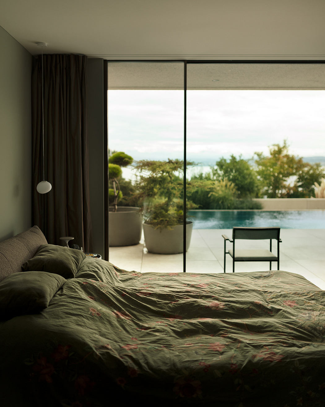 Modern bedroom with large window overlooking a pool.