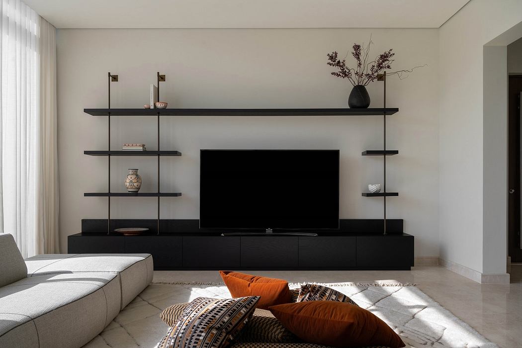 Modern living room with minimalist black shelving, TV, and neutral sofa.