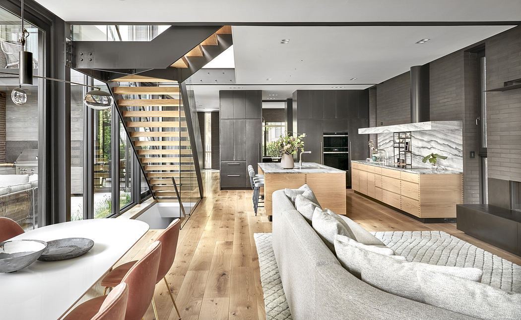 Modern open-plan kitchen and living area with wooden floors and staircase.