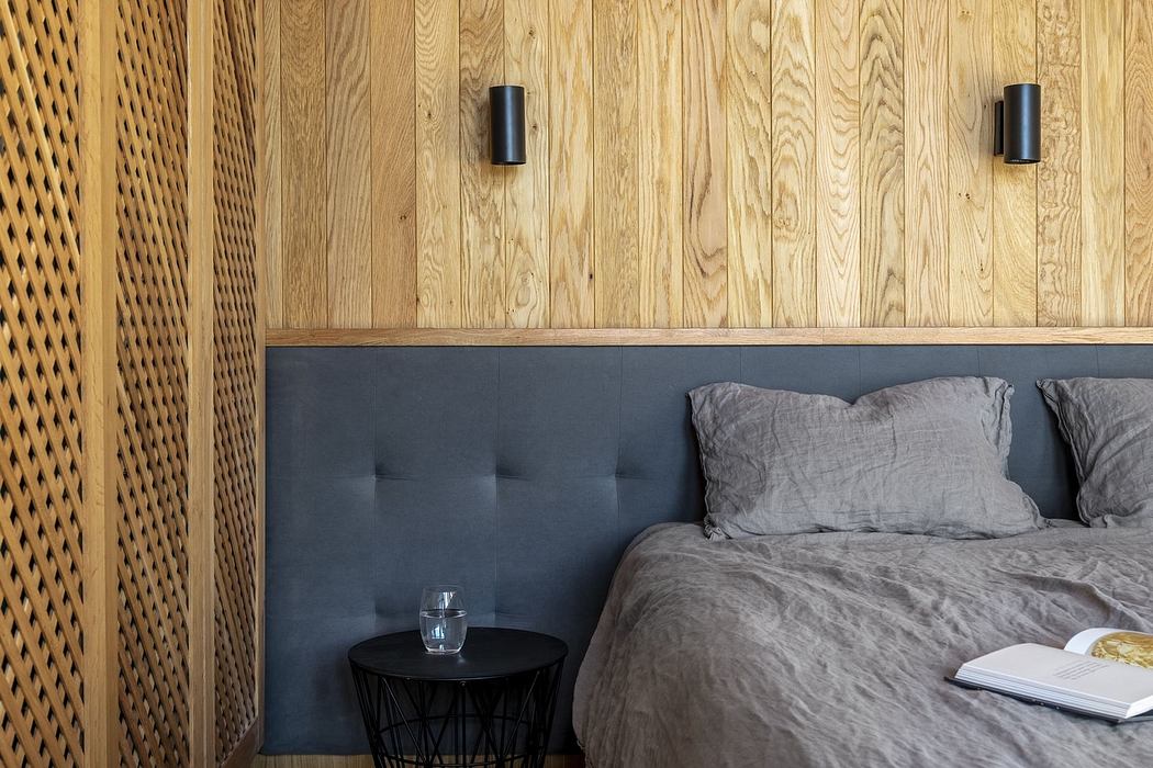 Modern bedroom with wooden wall paneling and grey bedding.