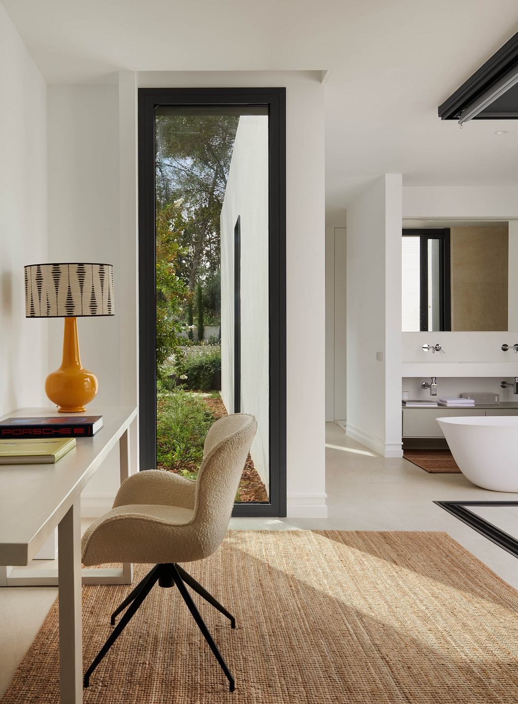 Modern room with desk, chair, lamp, and view of the bathroom.