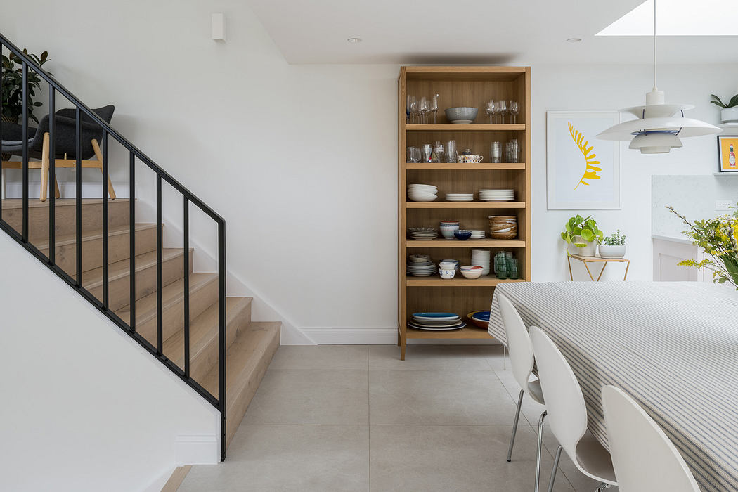 Modern dining room with wooden staircase and shelving unit.