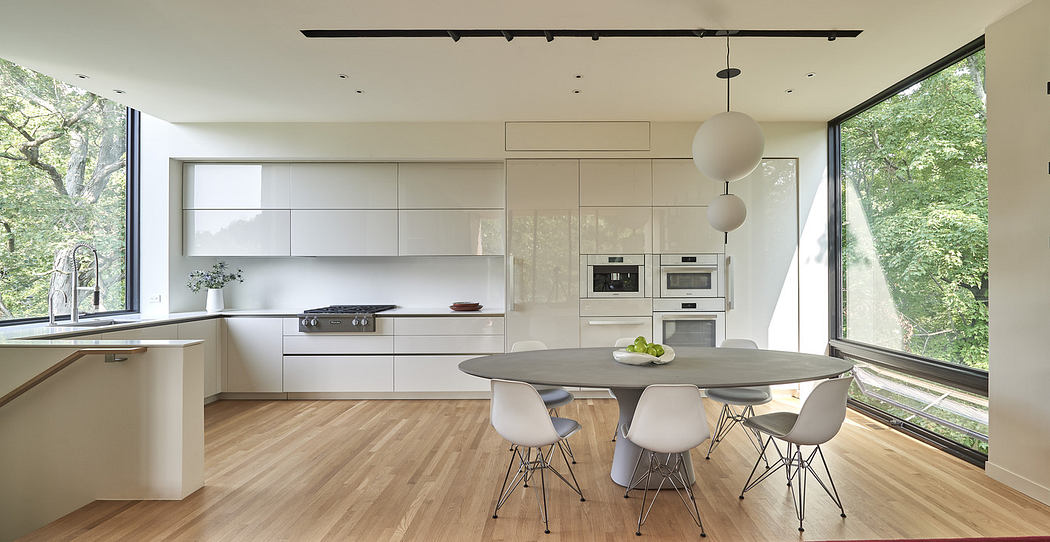 Modern kitchen with white cabinets, dining table, and large window.