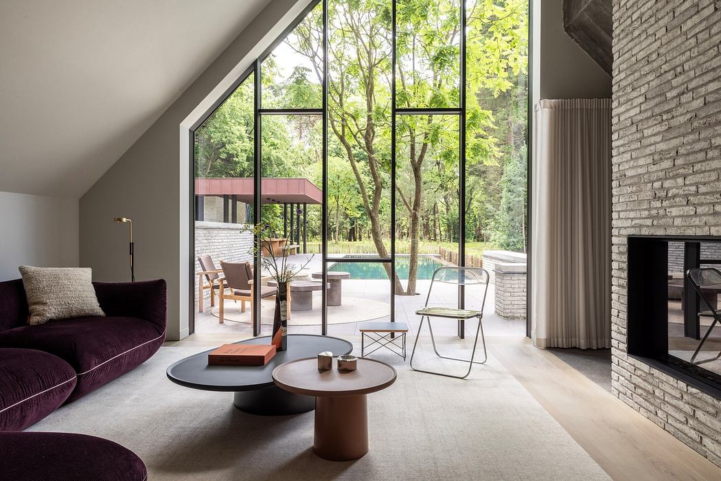 Modern living room with large windows overlooking a forest and minimalist furniture.
