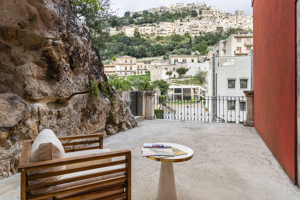 Outdoor patio with chair, table, and view of hillside buildings.