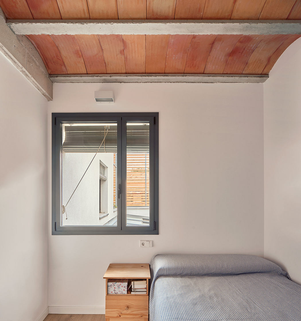 Minimalist bedroom with exposed brick ceiling and simple furnishings.
