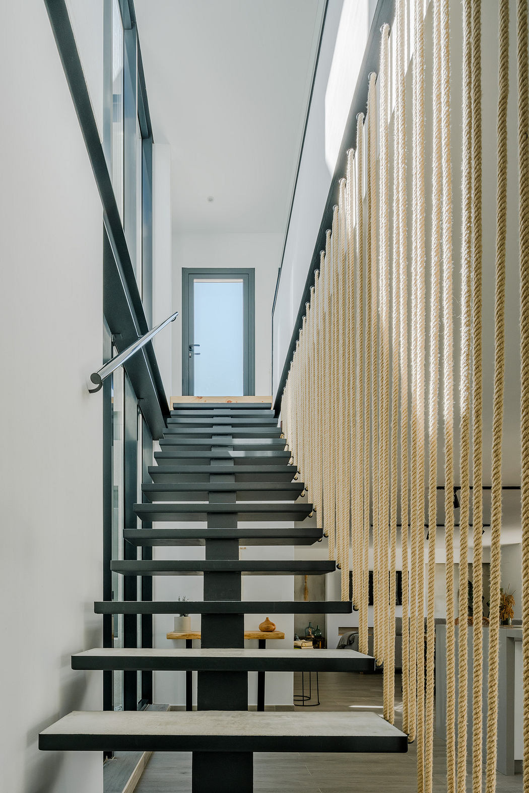 Modern staircase with black steps, metal railing, and wood slat wall.