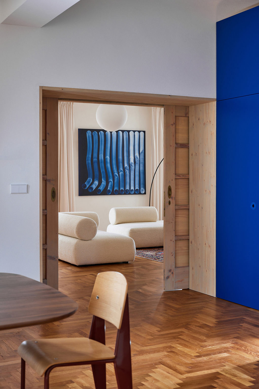 Modern room with blue accent wall, wooden details, herringbone floor, and