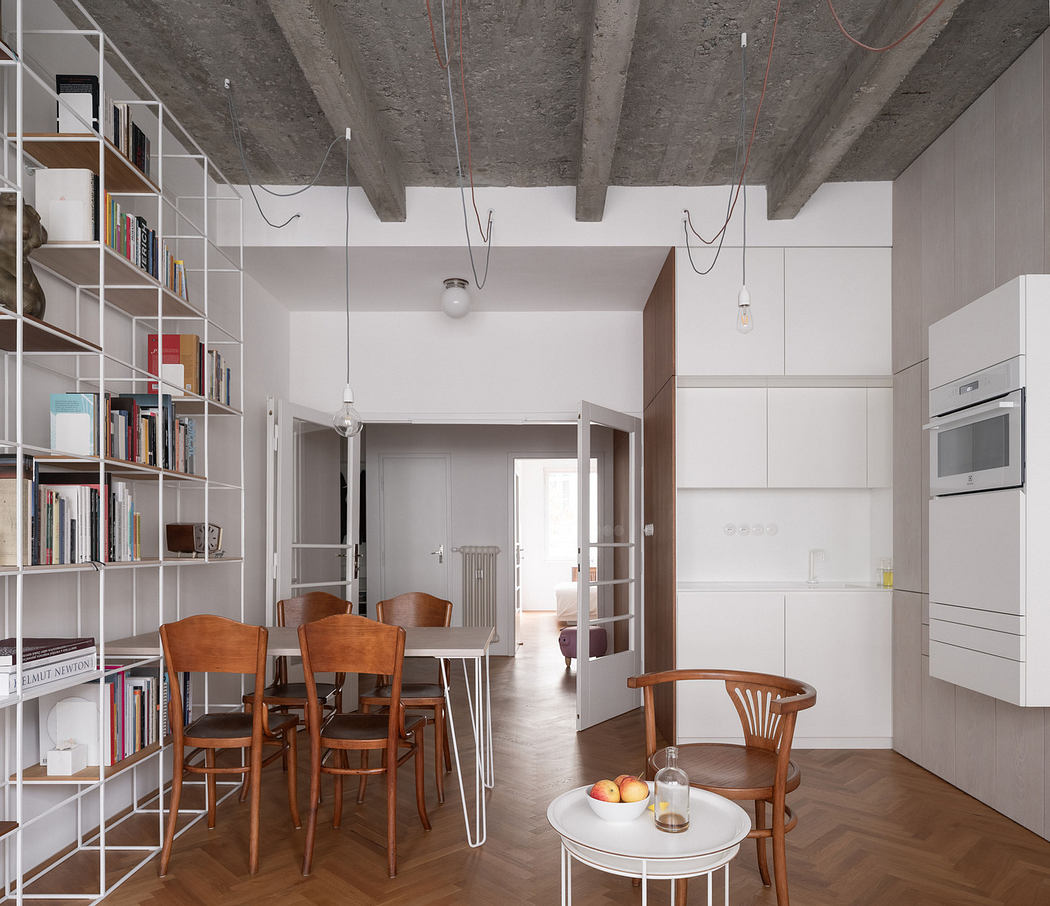 Modern minimalist interior with exposed concrete ceiling and bookshelf partition.