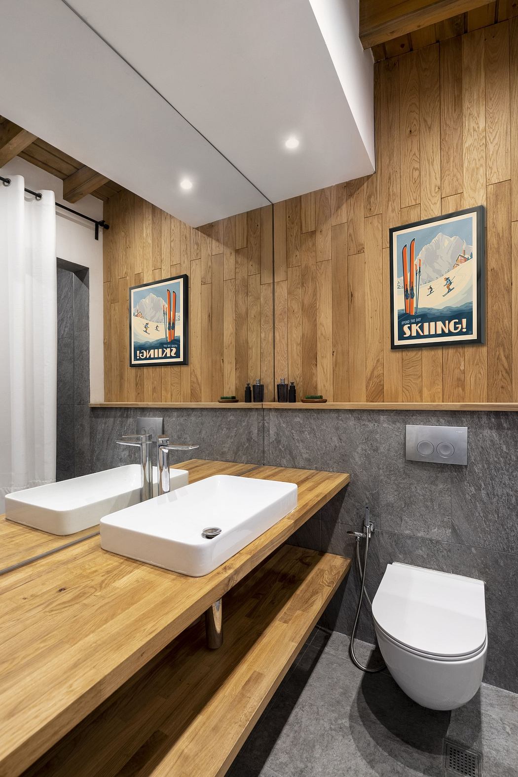 Modern bathroom with wooden accents, double sinks, and vintage ski posters.