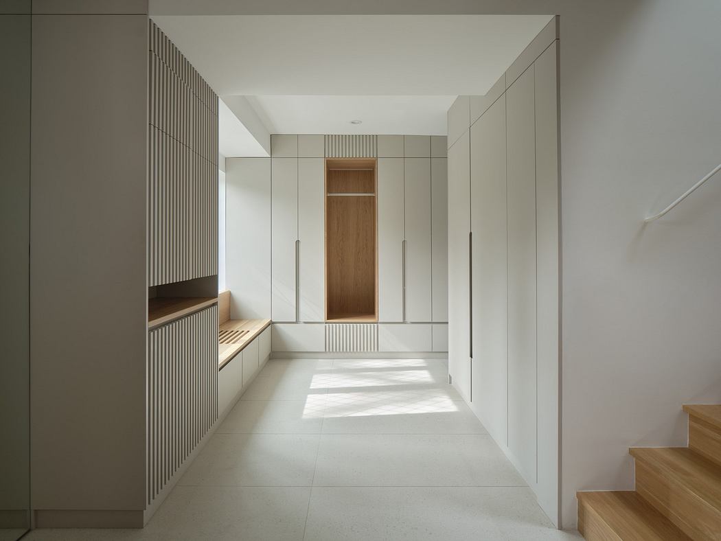 Minimalist hallway with white walls, built-in cabinets, and wooden accents.