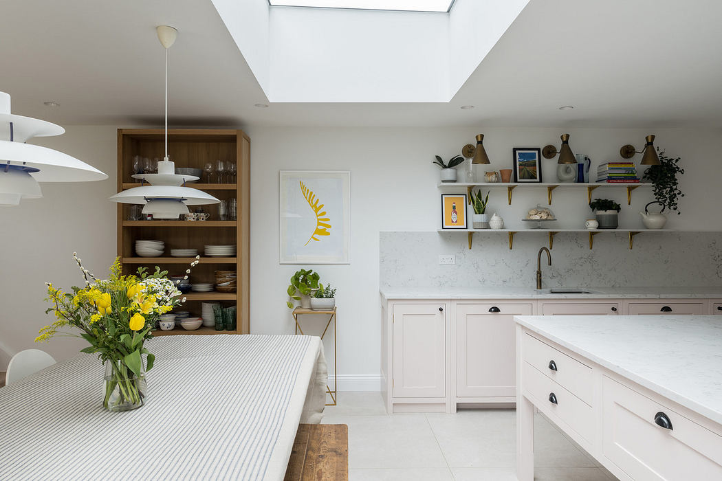 Modern kitchen interior with skylight, pastel cabinetry, and dining area