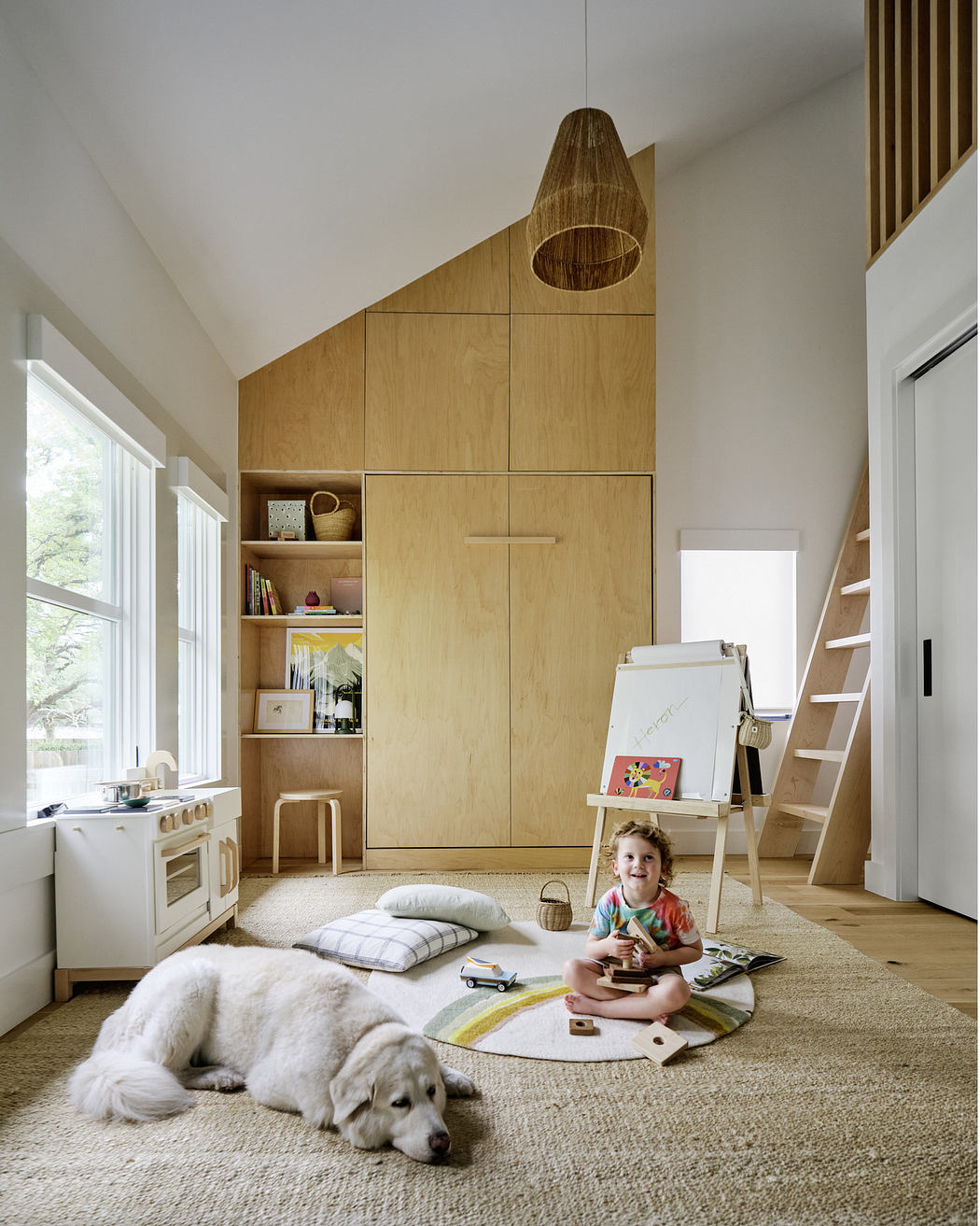 A child plays on a rug in a bright, modern room with wooden cabinetry