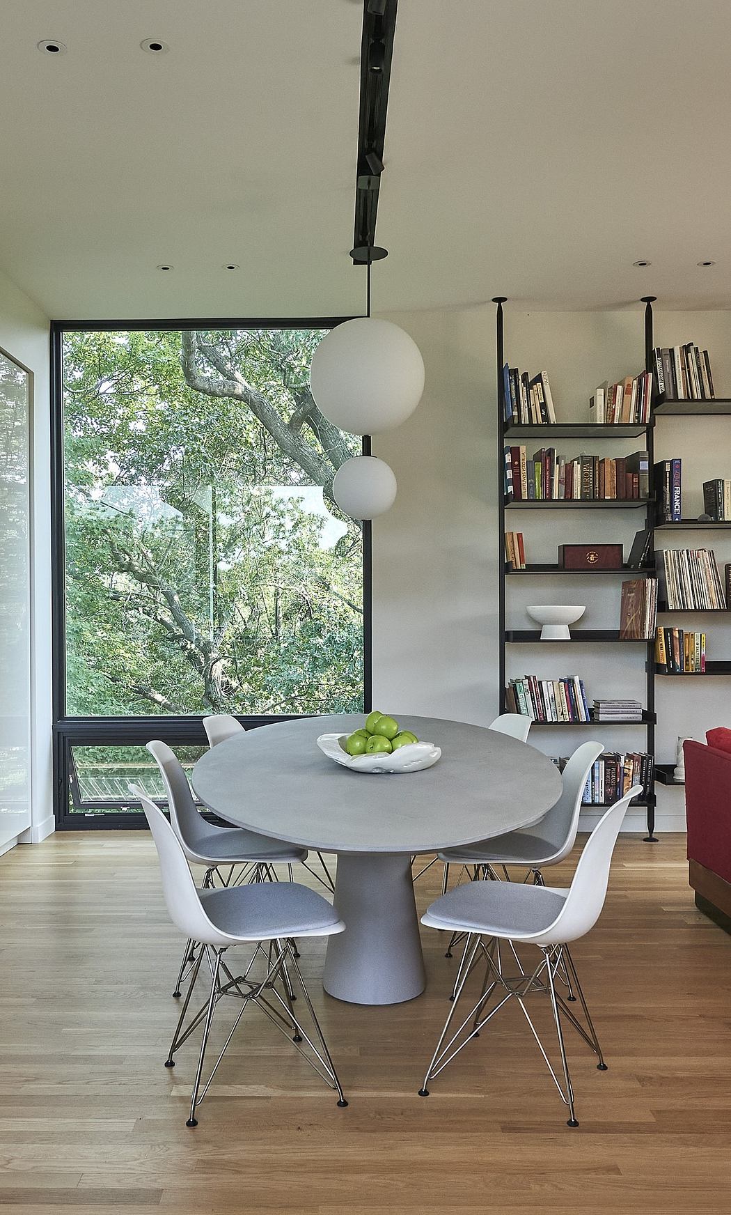 Modern dining area with bookshelves, large window, and unique pendant light.
