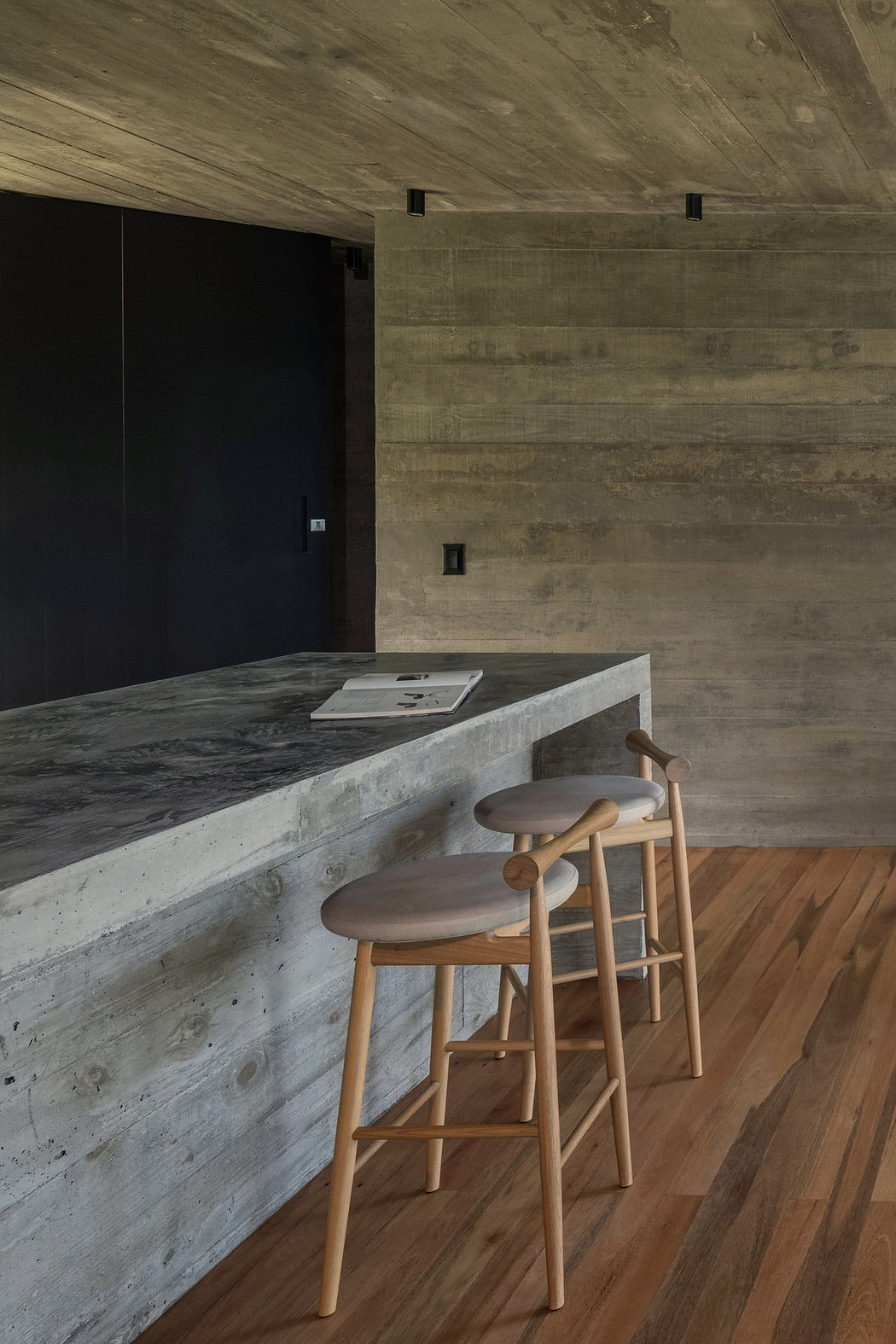 Modern kitchen with concrete finish and wooden stools.