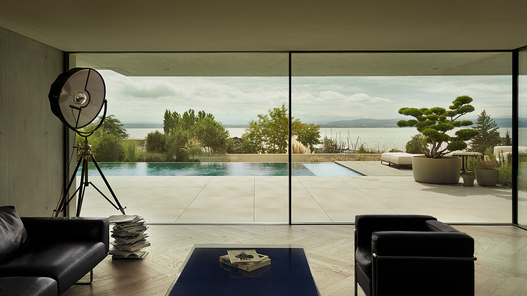 Modern living room with glass walls overlooking a pool and lake.