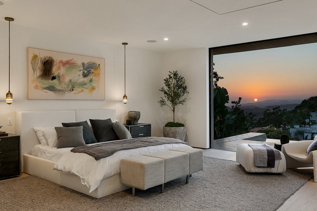 Modern bedroom with large window showing a sunset view.