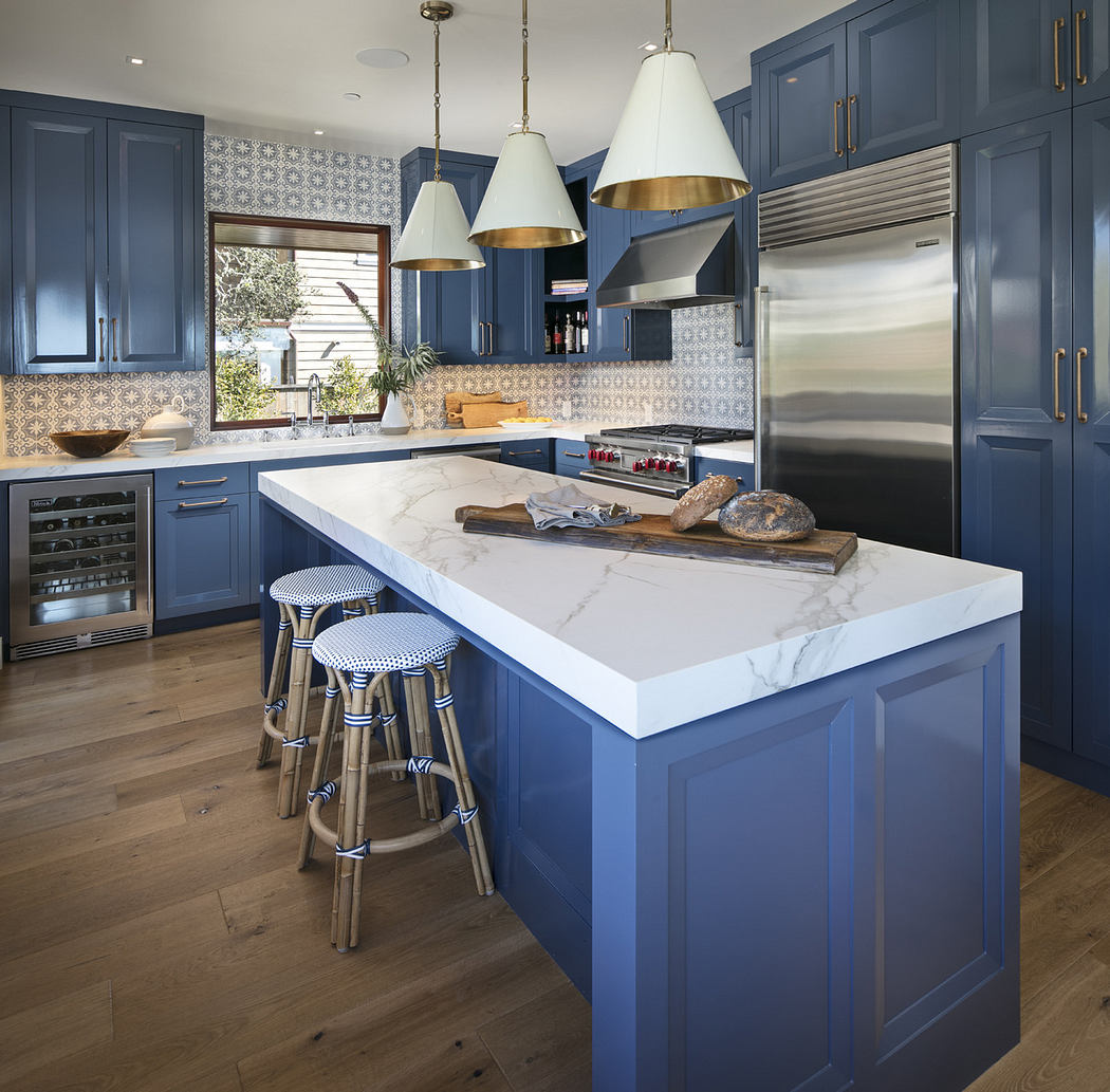 Modern kitchen with blue cabinets, white countertops, and gold pendant lights.
