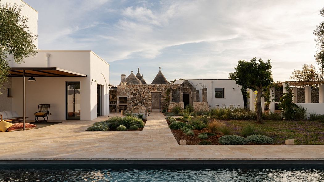 Modern villa with pool and traditional trullo houses in the background.