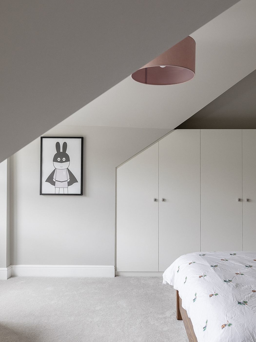 Minimalist attic bedroom with sloped ceiling and built-in wardrobes.