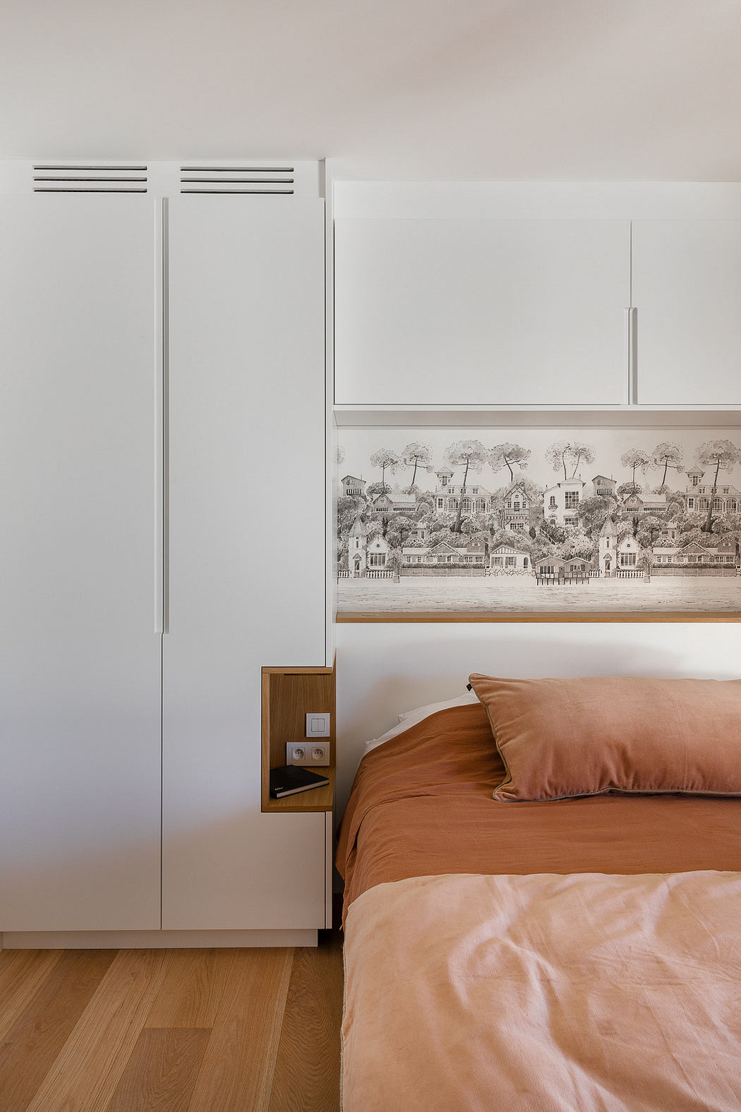 Minimalist bedroom with white closet, wooden floor, and framed artwork.