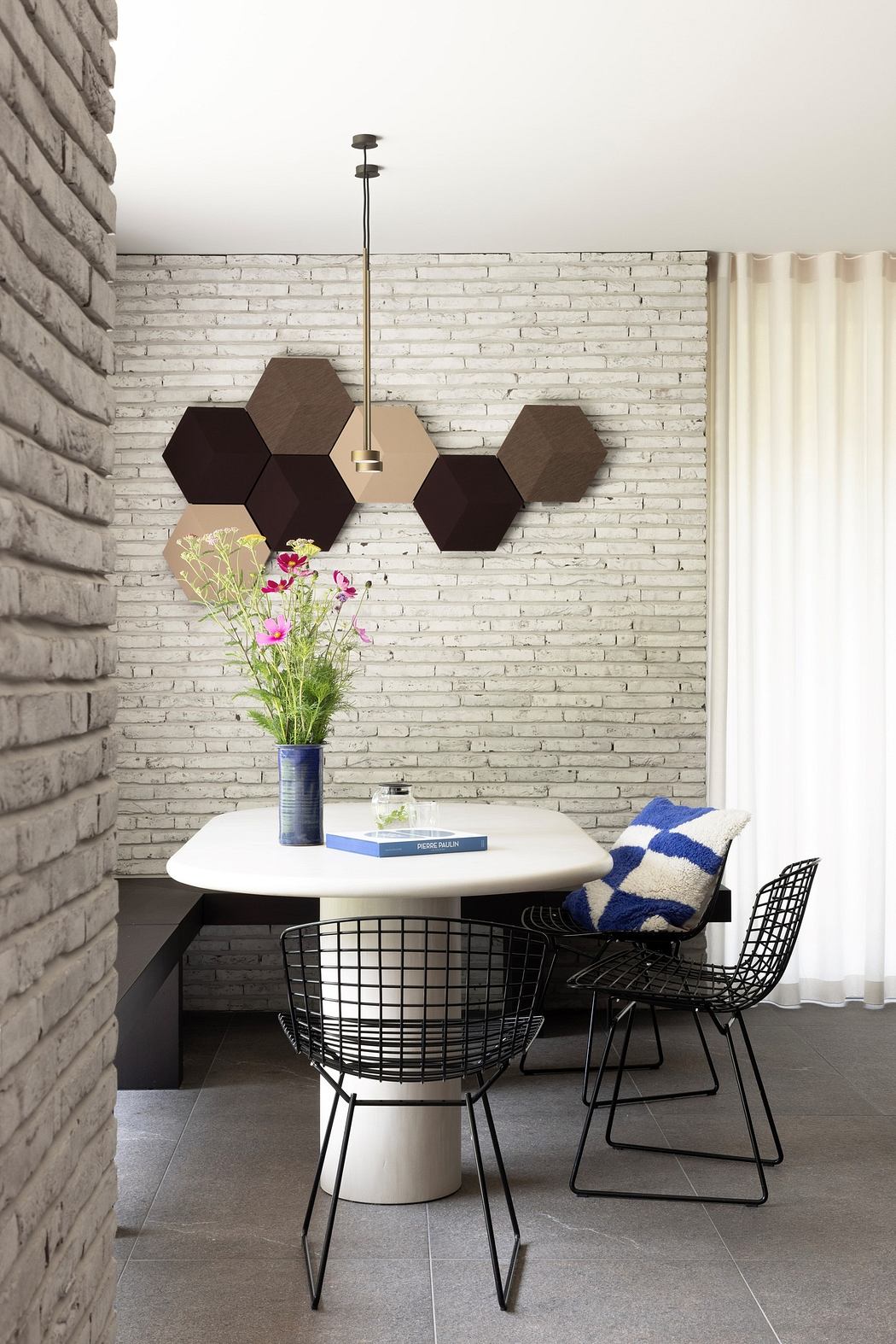 Modern dining space with hexagonal wall decor, brick wall, and designer chairs.