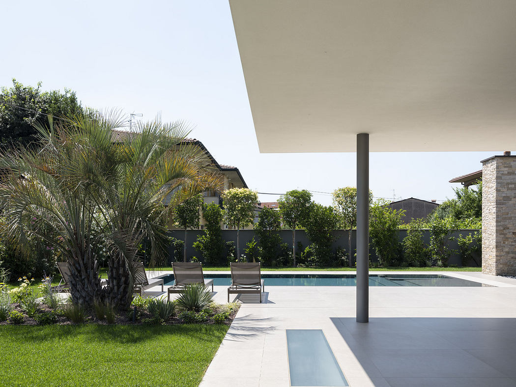 Modern backyard with a pool, patio, and loungers under a wide overhang