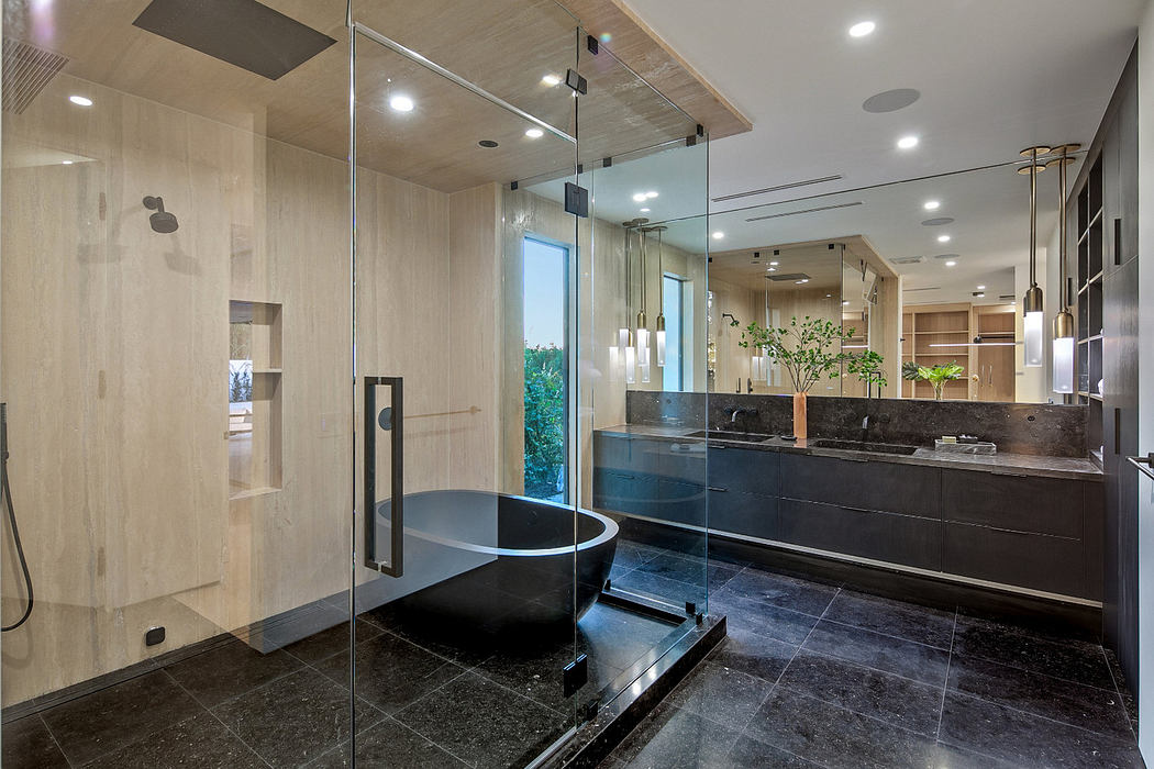 Modern bathroom with glass shower, black bathtub, and wooden accents.