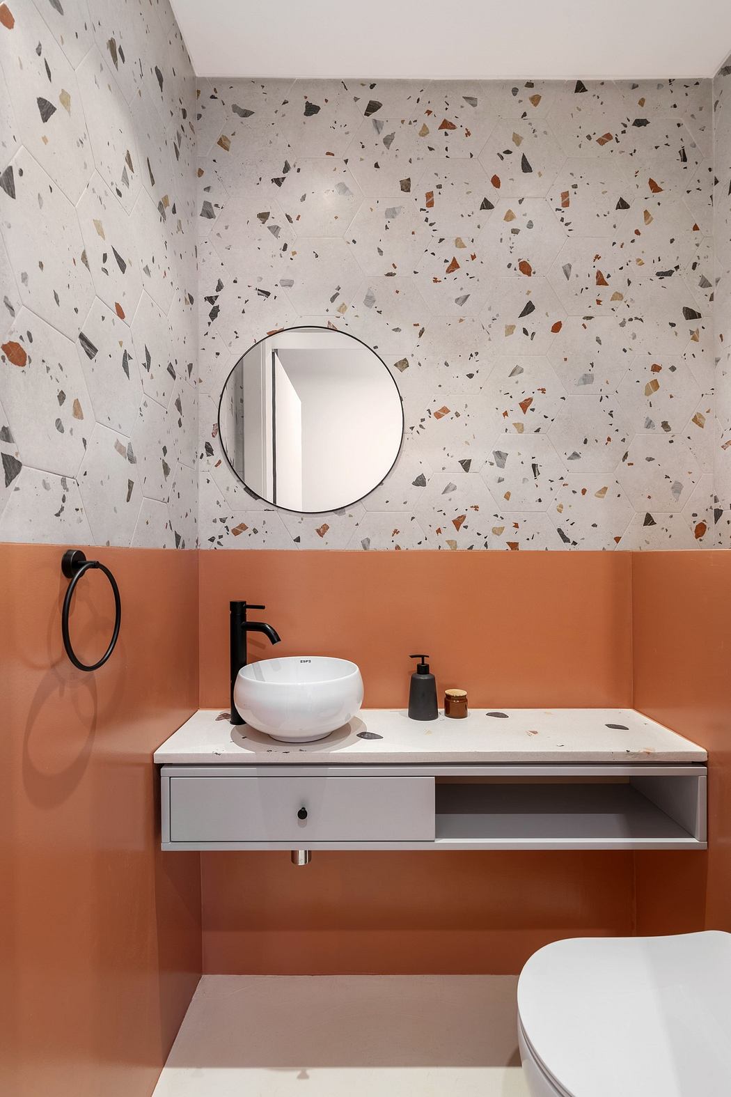 Modern bathroom with terrazzo wall and peach-colored vanity.