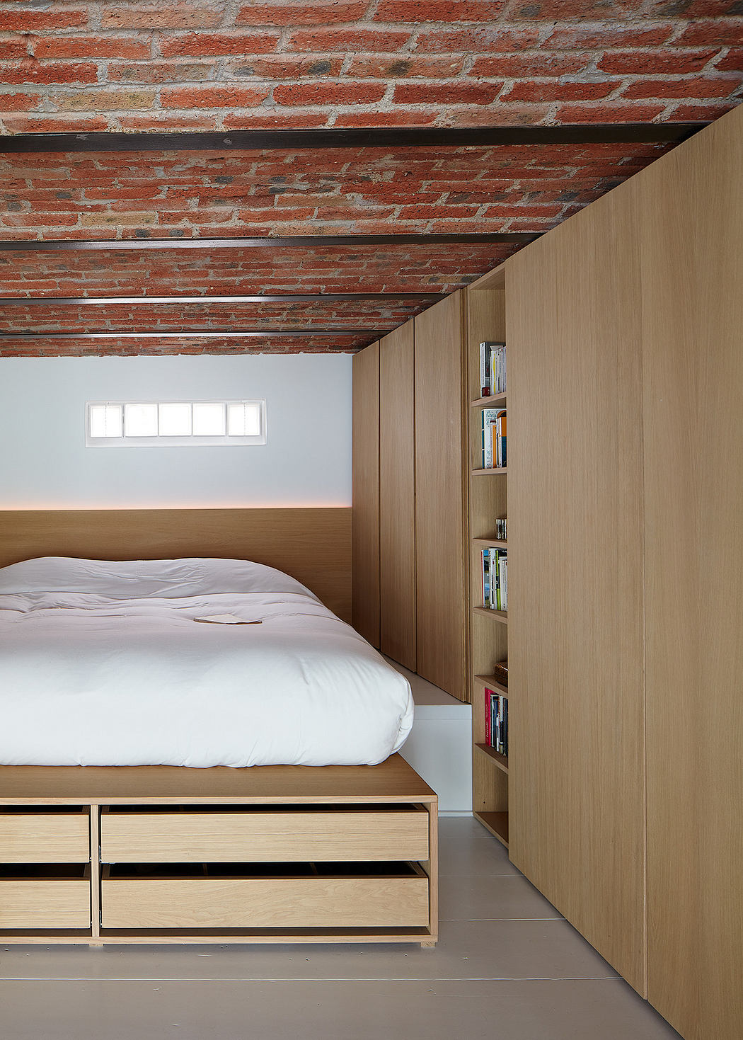 Modern bedroom with exposed brick ceiling and built-in wooden bookshelf.