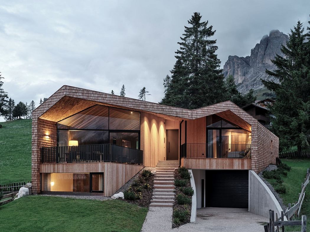 Modern wooden house with large windows nestled in a mountainous area.