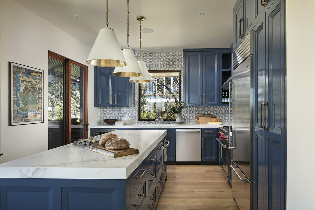 Modern kitchen with blue cabinets, white countertops, and pendant lights.