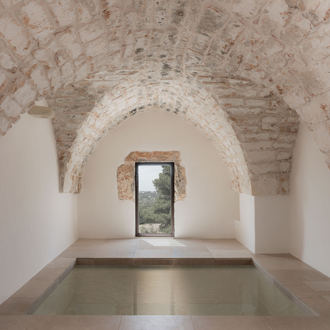 Minimalist interior with arched stone ceiling and central glass door.