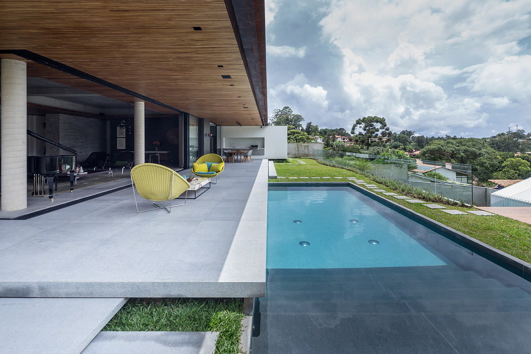 Modern house with open patio, stylish chairs, and a pool.