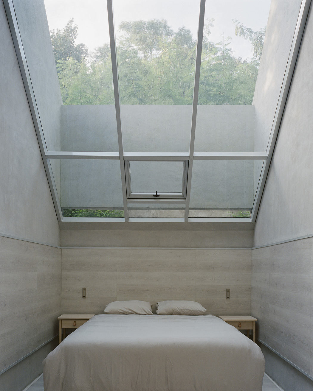 Minimalist bedroom with large skylight and concrete walls.