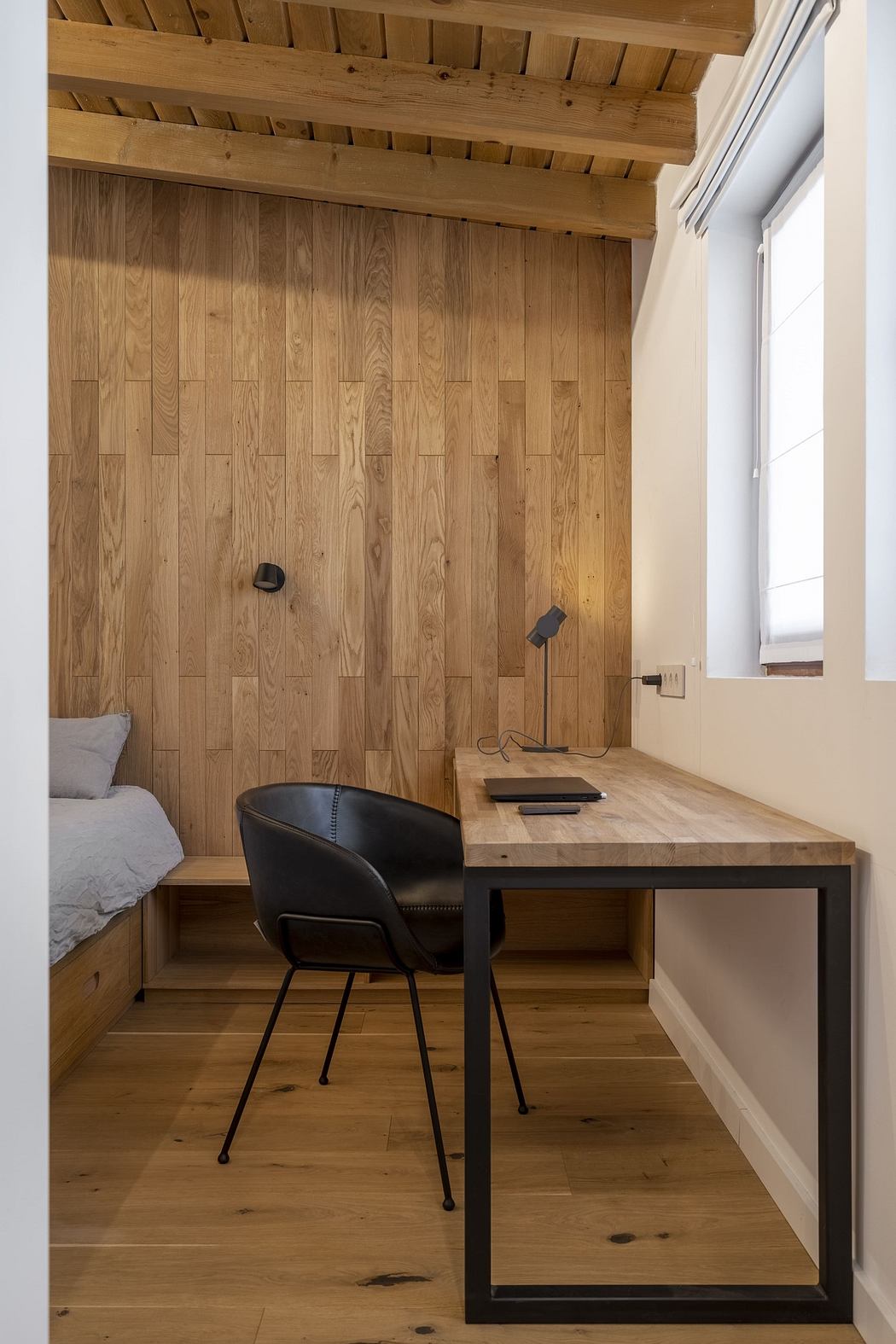Minimalist wooden home office with a sleek desk and black chair.