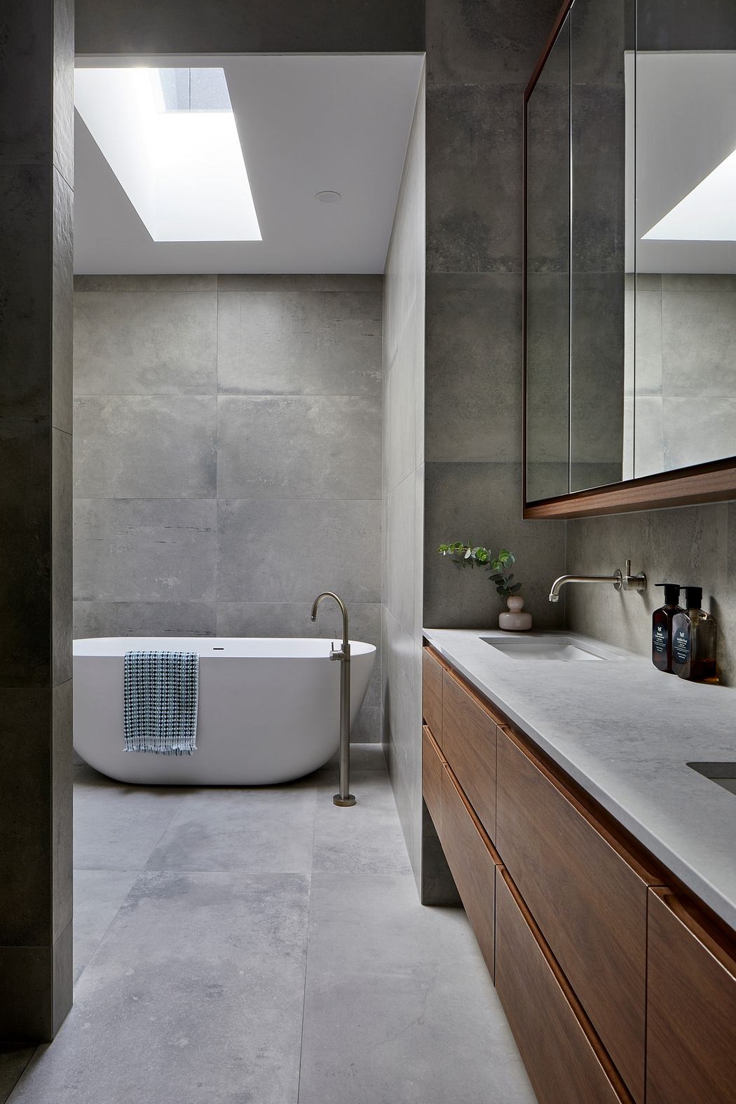 Modern bathroom with a freestanding tub, skylight, and minimalist vanity