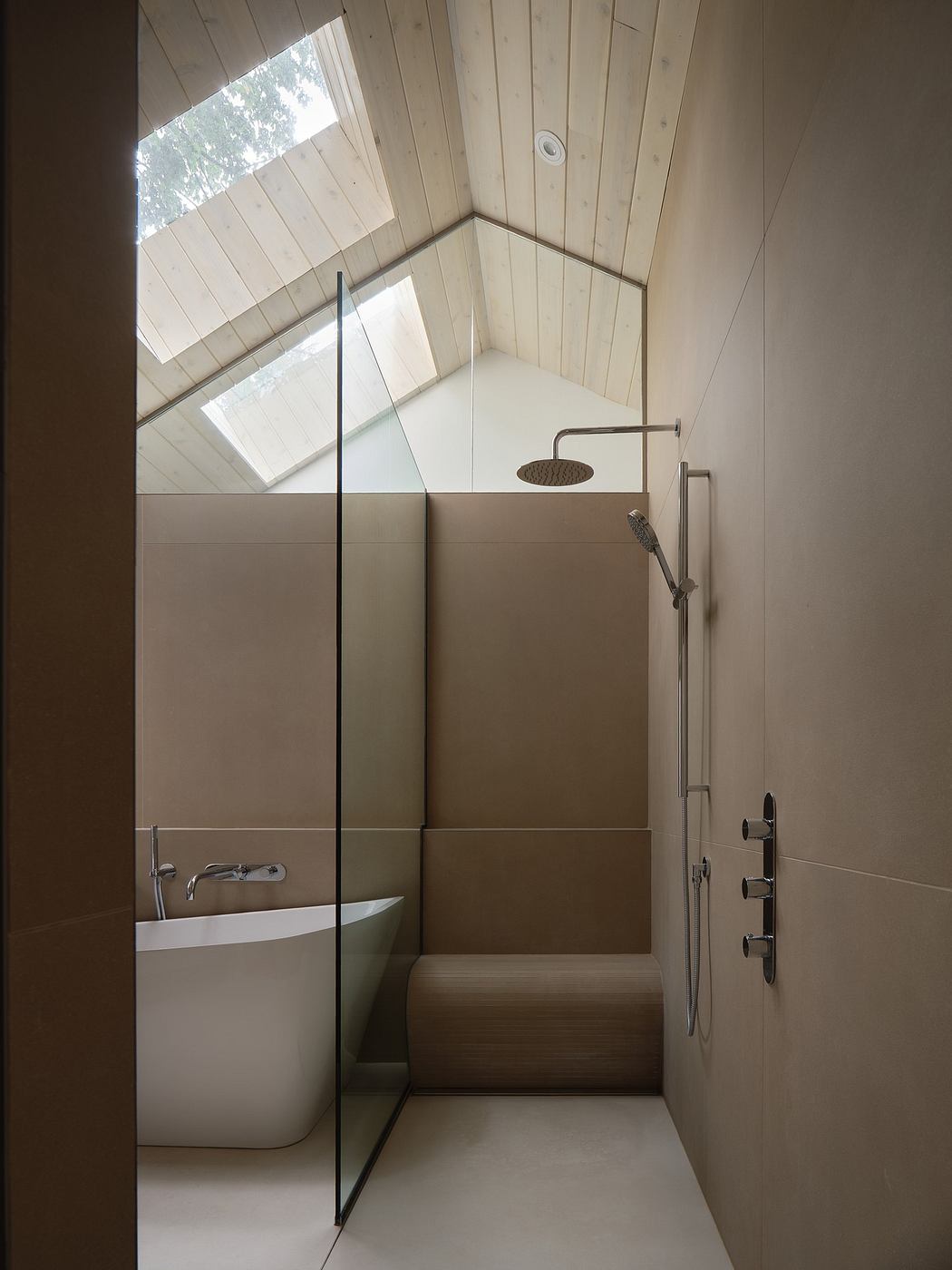 Modern bathroom with sloped ceiling, skylight, and neutral tones.