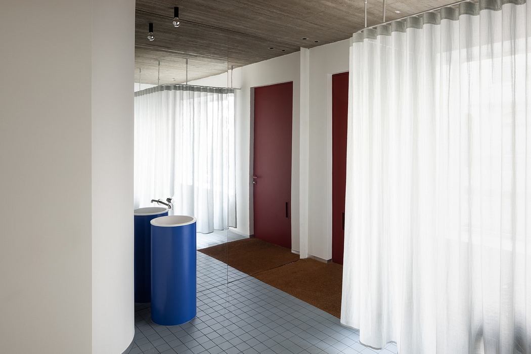 Modern minimalist interior with sheer curtains, a blue column, and red doors.