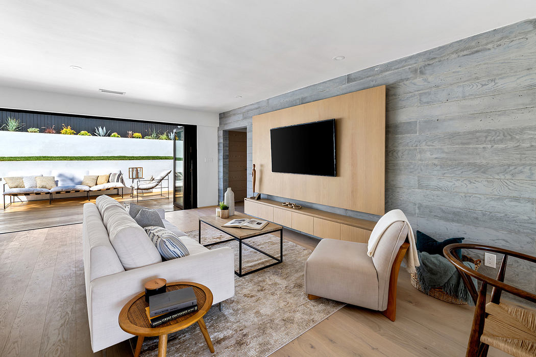 Modern living room with sleek furniture and large TV on wood panel wall.