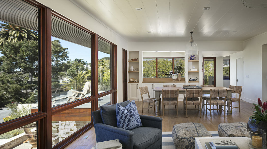Modern living room with large windows, wood floors, and open dining area.