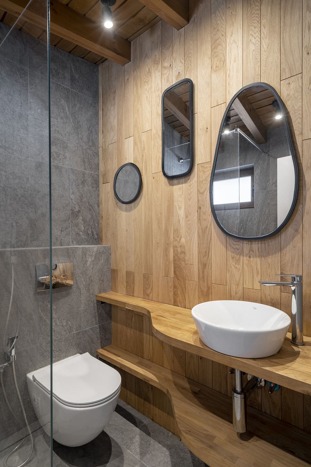 Modern bathroom with wooden walls, a vessel sink, and oval mirrors.