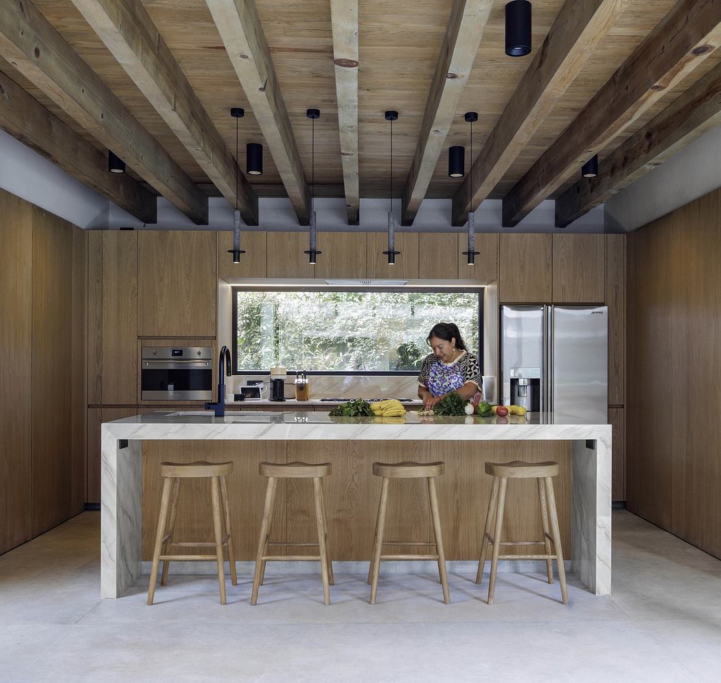Modern kitchen with wood finishes and a person prepping food at the island.